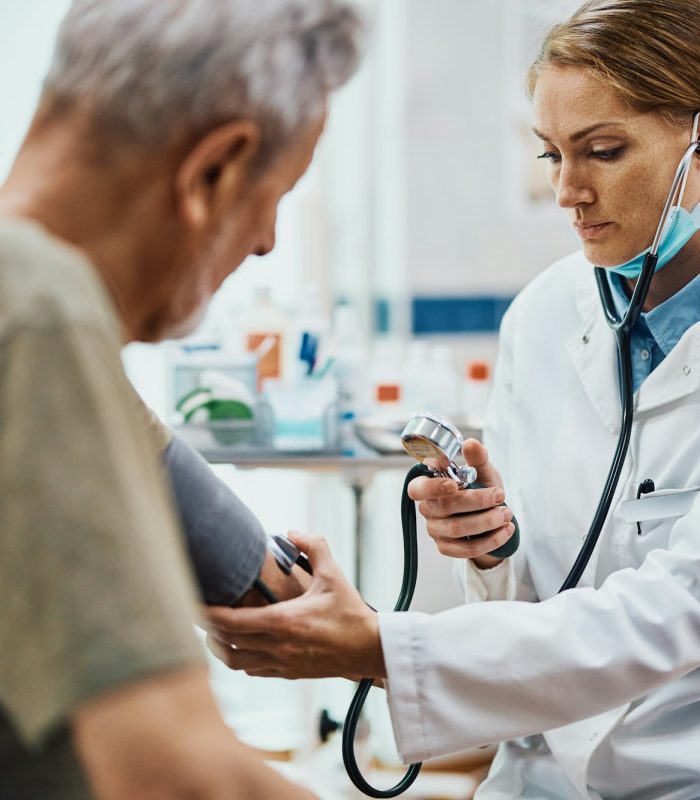 Female doctor doctor measuring senior man's blood pressure at medical clinic.